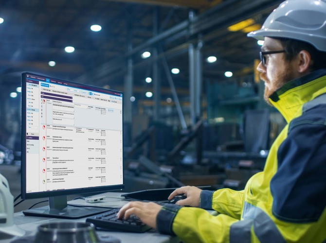 Een man met een veiligheidshelm die een computer gebruikt