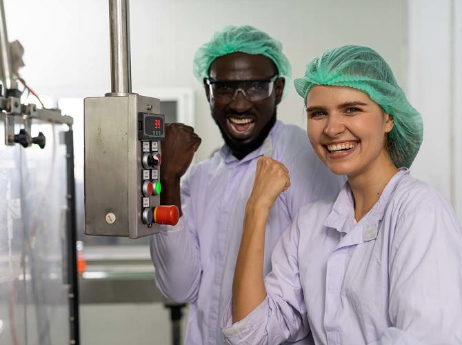 Een man en vrouw in witte jassen en groene haarnetten