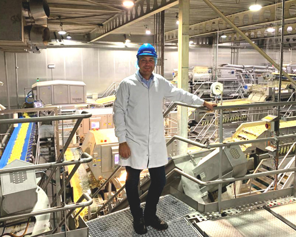 Een man in een witte jas en blauwe helm die op een metalen platform staat